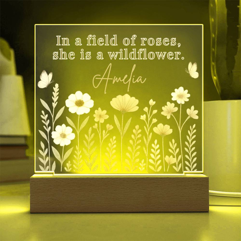 Decorative light with floral design and text 'In a field of roses, she is a wildflower.