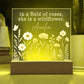 Decorative light with floral design and text 'In a field of roses, she is a wildflower.