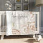 Floral crib blanket with personalized text printed on it in a nursery setting.