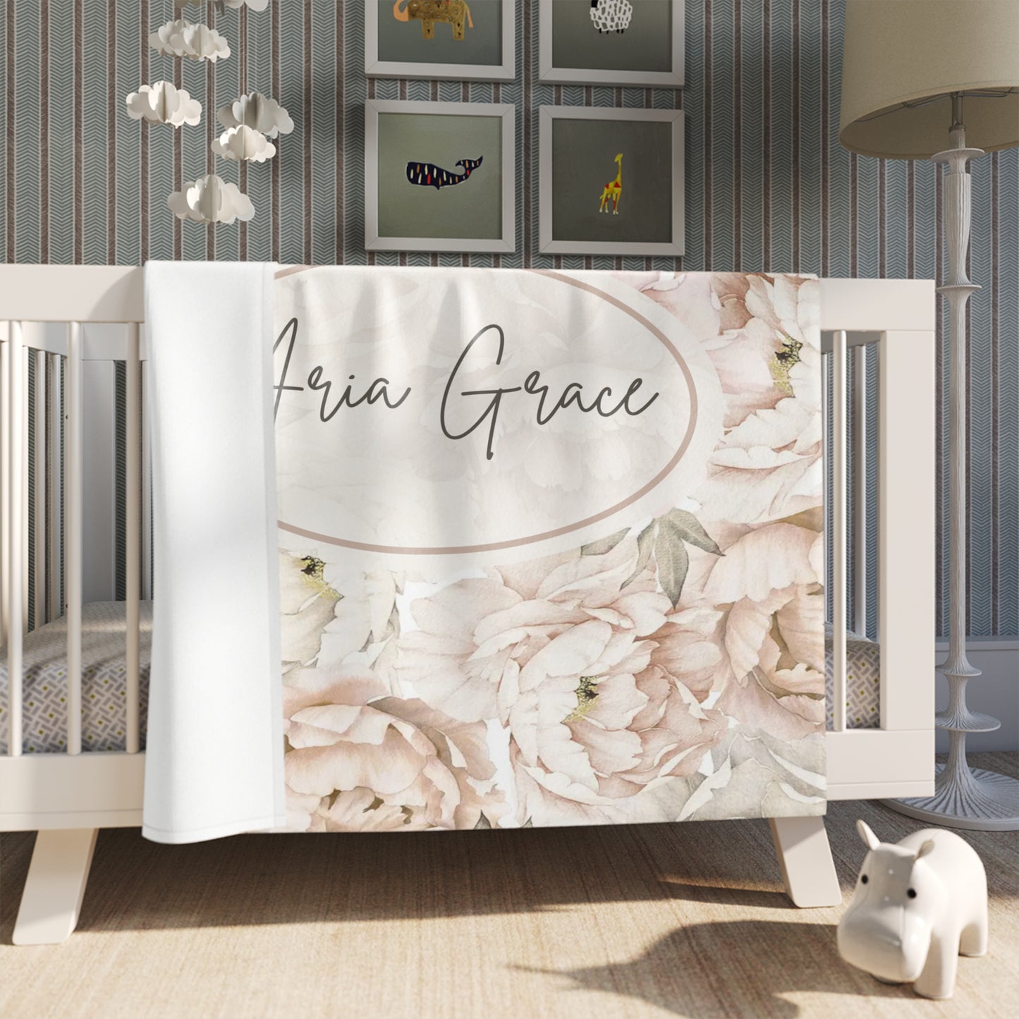 Floral crib blanket with personalized text printed on it in a nursery setting.