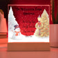 Decorative Christmas sign with a snowman, tree, and family names on a red background.