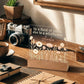 Decorative glass panel with floral design and text on a wooden desk with camera and coffee cup.